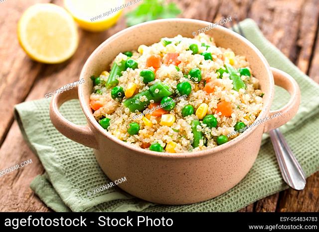 Fresh homemade cooked white quinoa with colorful vegetables (green peas, sweet corn kernels, green beans, carrots) and parsley in bowl