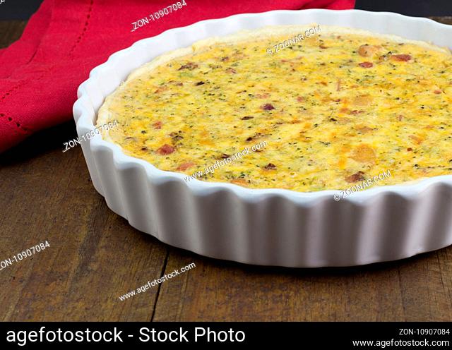 Quiche with cheese, bacon and mushroom on rustic wooden table - Open pie in white dish with selective focus