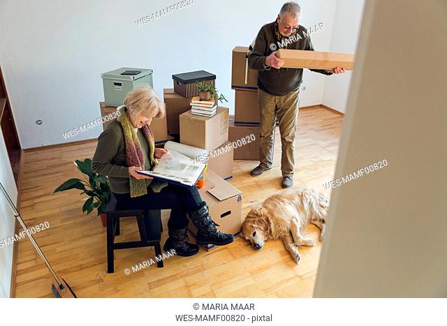 Senior couple with dog surrounded by cardboard boxes in an empty room