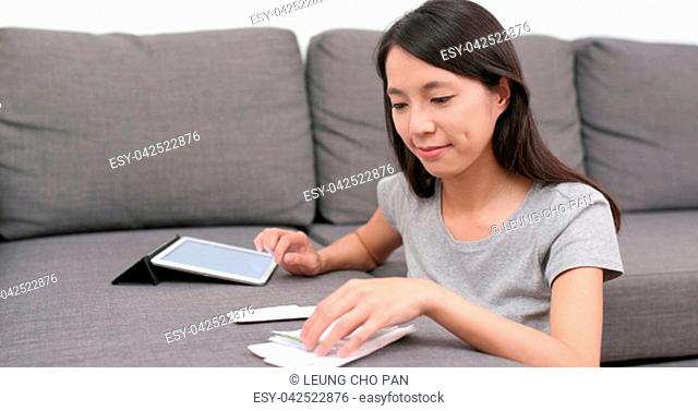 Woman record the daily expense of tablet computer at home