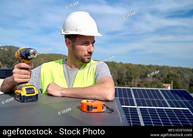 Engineer with drill installing solar panels on sunny day