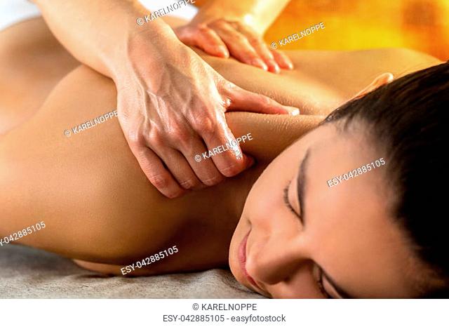 Close up of physiotherapist massaging upper neck and shoulder on young woman in spa
