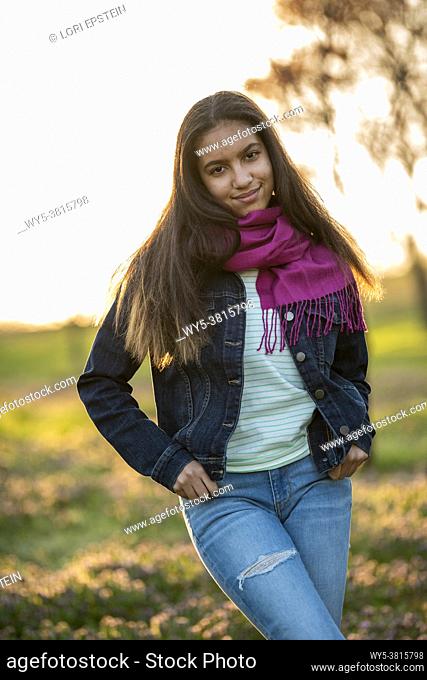 Outdoor portrait of mixed race teenage girl in a grove of cherry trees at sunset in the springtime