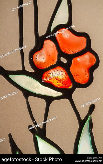 Close up view of colorful stained glass depicting a poppy flower as a motif