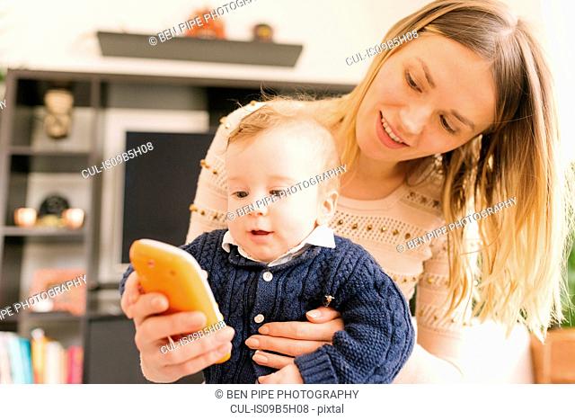 Mother holding baby with toy smartphone