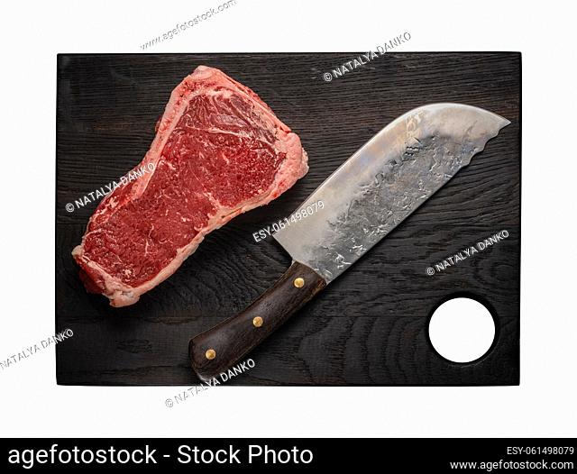 Raw juicy piece of beef meat on the bone lies on a wooden cutting board