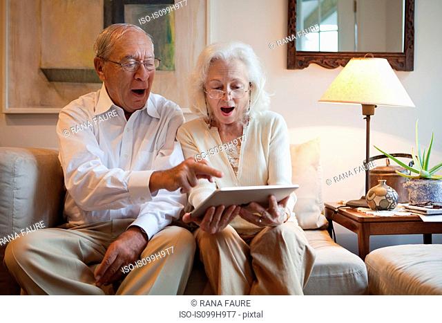 Senior couple using computer tablet at home