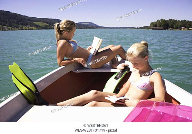 Girls (13-15) sitting on boat, reading, side view