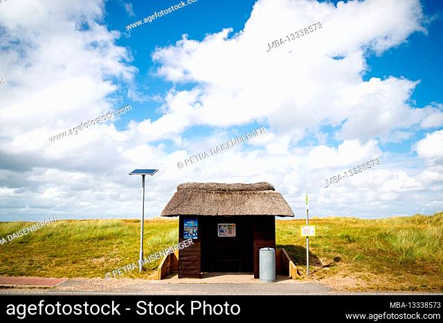 A thatched-roof bus stop with a solar panel behind the dune, Sylt, Schleswig-Holstein, Germany