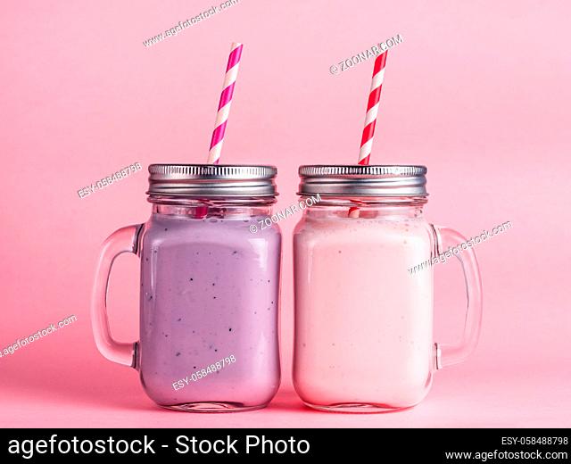 Strawberry and blueberry smoothie in mason jar glass on pink background