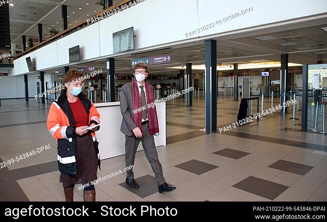 22 February 2021, Brandenburg, Schönefeld: Engelbert Lütke Daldrup, airport boss, and an airport employee walk through the deserted check-in hall on what is...