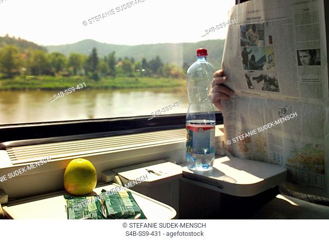 Person reading newspaper on a train, selective focus