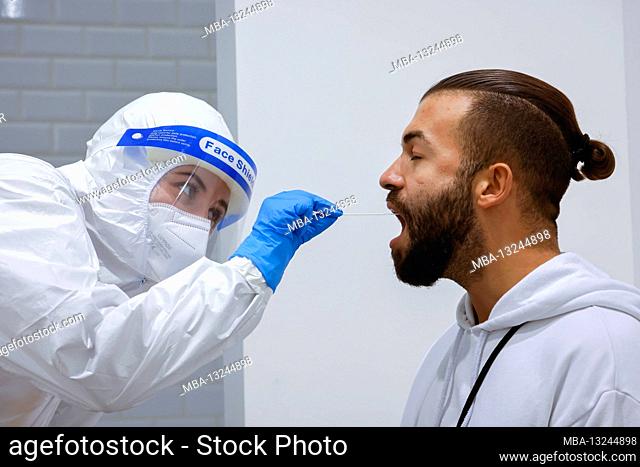 Cologne, North Rhine-Westphalia, Germany - Covid rapid test at the Medicare test center, throat swab on cotton swab (posed scene)