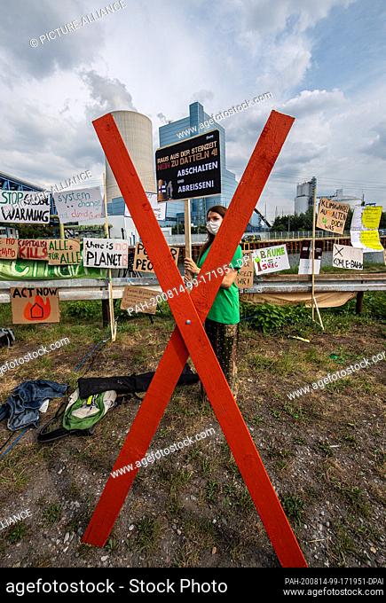14 August 2020, North Rhine-Westphalia, Datteln: A climate activist is standing in front of the coal-fired power plant Datteln 4 on the Dortmund-Ems canal in...