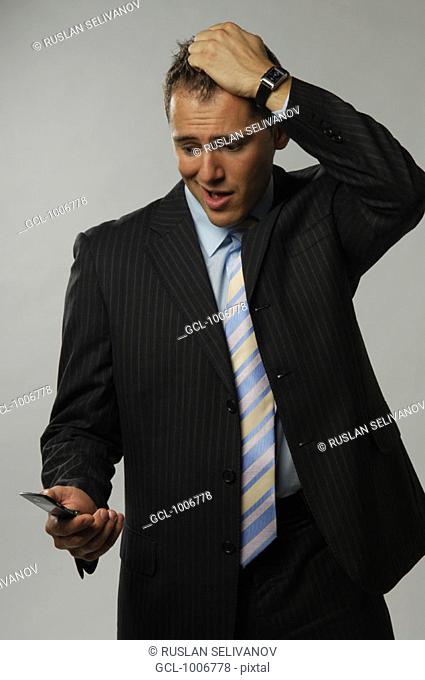Businessman tearing his hair while looking at his mobile phone