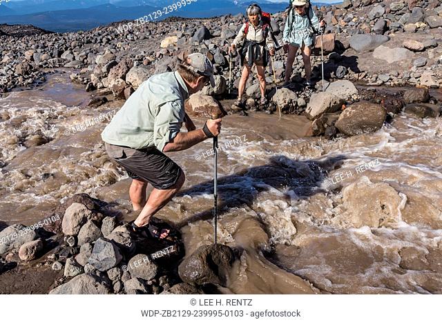 Lee Rentz crossing the raging brown waters of a branch of Muddy Fork Creek coming off Lyman Glacier on Mt. Adams to assist Joan Michaels and Junko Waibel in the...