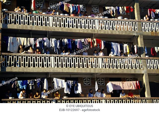 Laundry hanging on apartment balconies in the Xishuangbana area with residents looking down on street