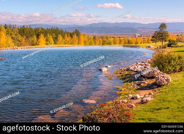 Beautiful autumn landscape view of the lake, pine trees, wooden chalets and mountains sunset background near Bansko, Bulgaria