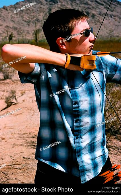 Young man shooting a bow and arrow in the desert