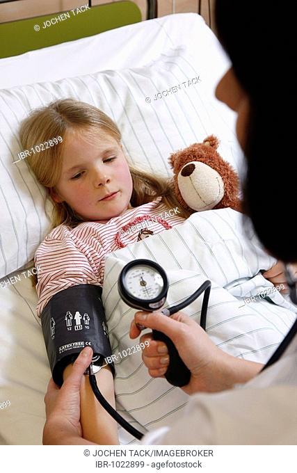 Nurse measuring blood pressure of a young patient, 7 years, in hospital