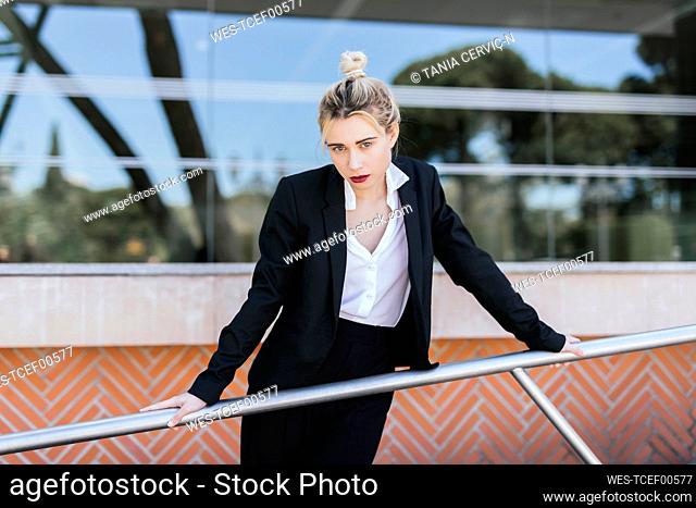 Portrait of young businesswoman wearing black pantsuit standing in front of an office building