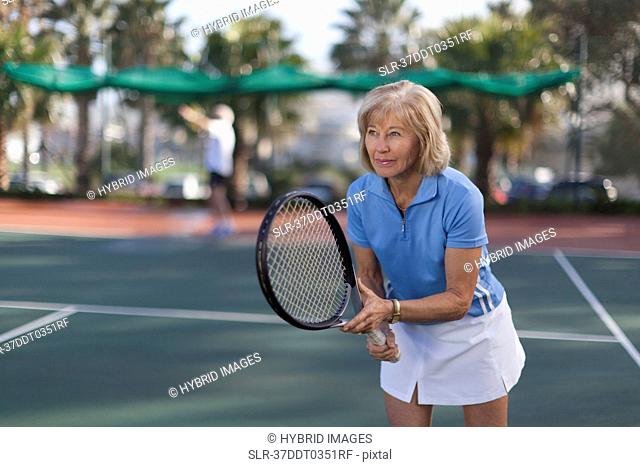 Older woman playing tennis outdoors