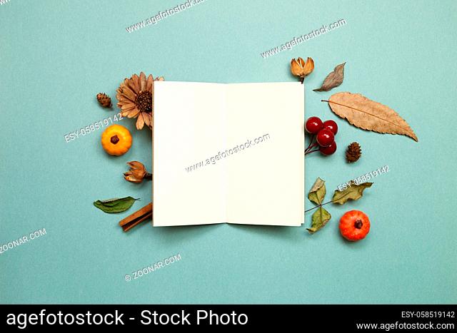 Autumn concept. Empty note paper with dry leaves on green background. flat lay, top view, copy space