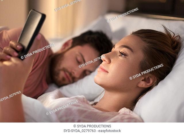 woman using smartphone while boyfriend is sleeping