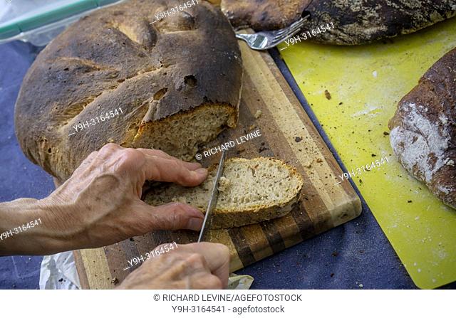 A baker cuts a slice of artisanal bread baked in a wood-fired oven in Brooklyn in New York on Sunday, August 19, 2018. (© Richard B. Levine)