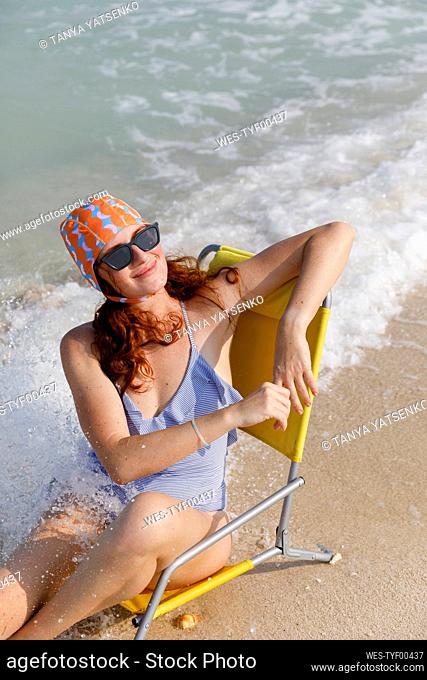 Happy woman sitting on chair enjoying at beach