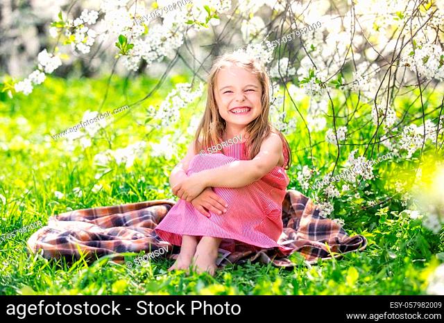 Happy little girl playing in spring cherry garden