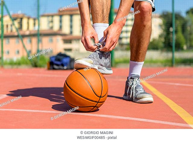 Young basketball player tying shoes