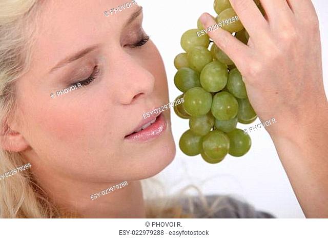 Woman holding a bunch of grapes next to her face