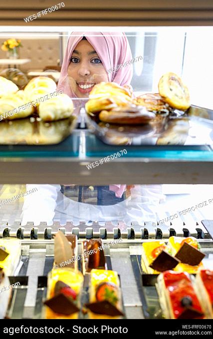 Smiling woman choosing pastries from display at store