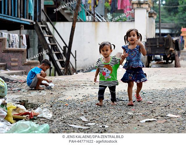 Two girls walk in the Chhba Anmpov Slum on the grounds of a Chinese graveyard in Phnom Penh, Cambodia, 10 December 2013. Unicef supports the local project 'Mith...
