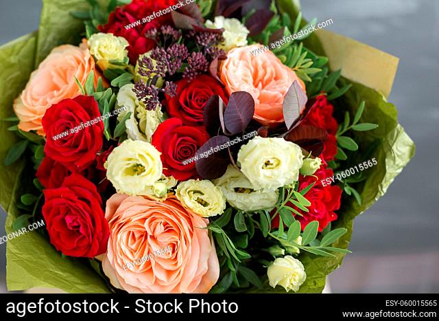 Bouquet in kraft paper. A simple bouquet of flowers and greens. on a gray background. In the autumn style. copy space