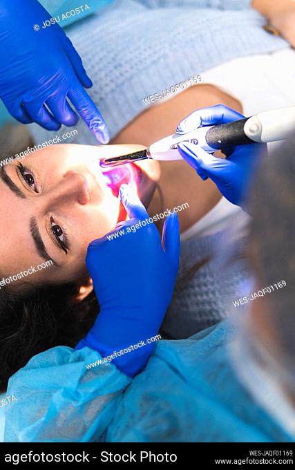 Dentist examining patient with equipment in medical clinic