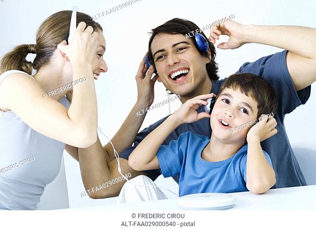 Family listening to CD player together, father and son using wireless headphones