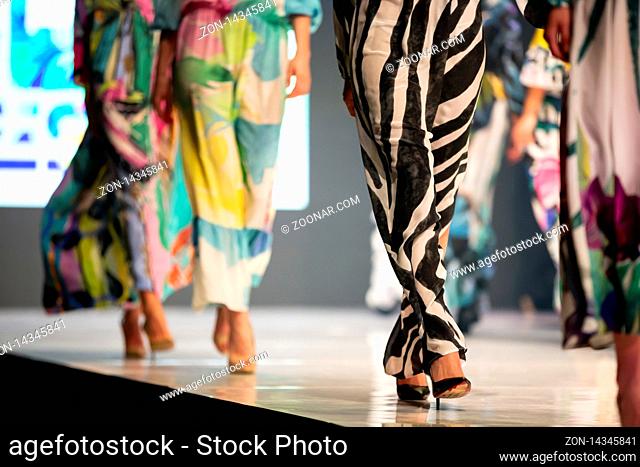 Female models walk the runway in beautiful colorful summer dresses during a Fashion Show. Fashion catwalk event showing new collection of clothes
