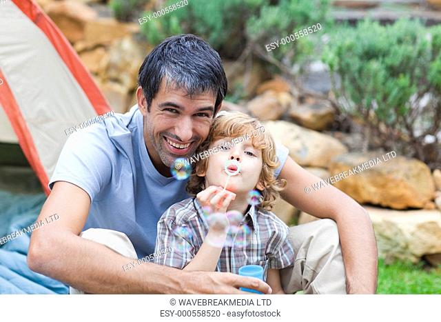 Father and son blowing bubbles in tent