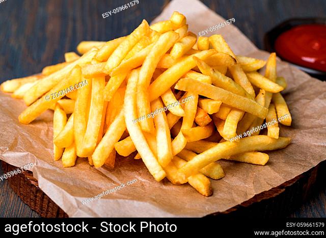 Tasty french fries on cutting board