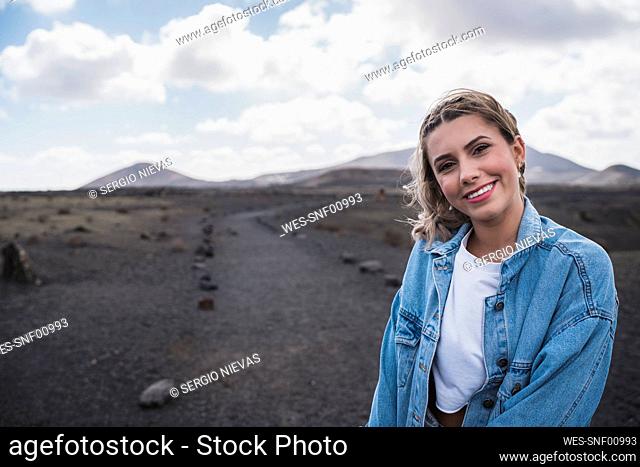 Young woman smiling while standing at Volcano El Cuervo, Lanzarote, Spain