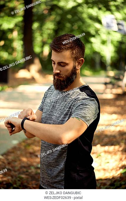 Sporty man in forest checking his smartwatch
