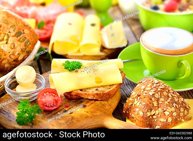 Rustikaler, bunter Frühstückstisch mit Käseröllchen und weiterer reichlicher Auswahl - Outside served colorful breakfast with a large selection of food and a...