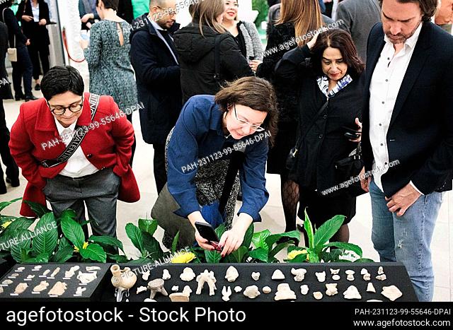 23 November 2023, Berlin: Guests look at a table with 75 museum objects after the signing of an agreement for the transfer of 75 museum objects from Germany to...
