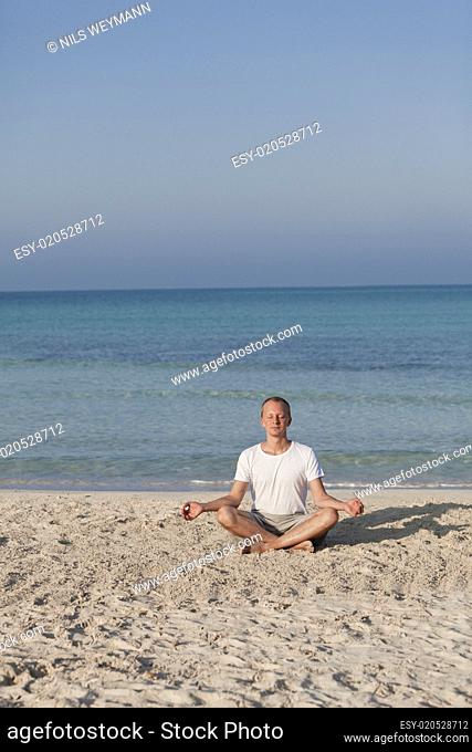 Mann macht yoga Sport am Strand Hochformat