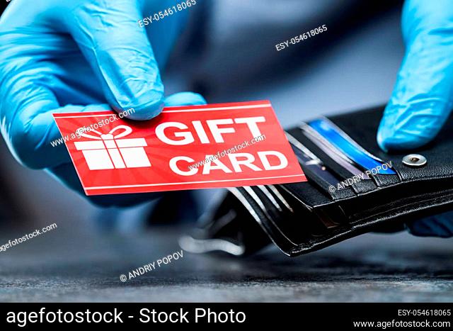 Consumer Taking Gift Card From Wallet In Gloves To Protect From Coronavirus