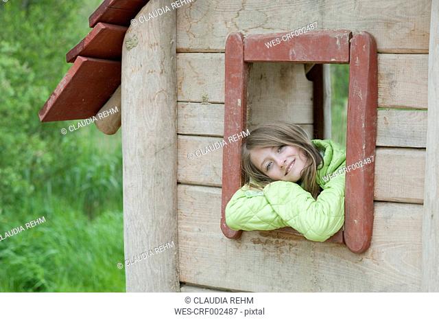 Germany, Bavaria, girl looking outside of the window of a wendy house