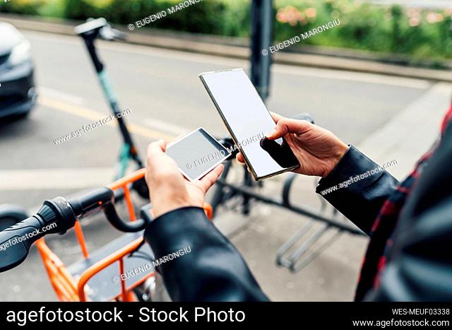 Woman with credit card using smart phone at bicycle parking station