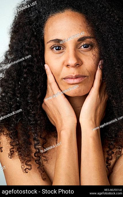 Serious curly haired woman touching face